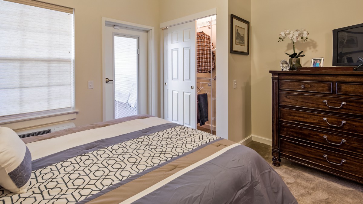 A cozy bedroom with a neatly made bed and an open closet door.