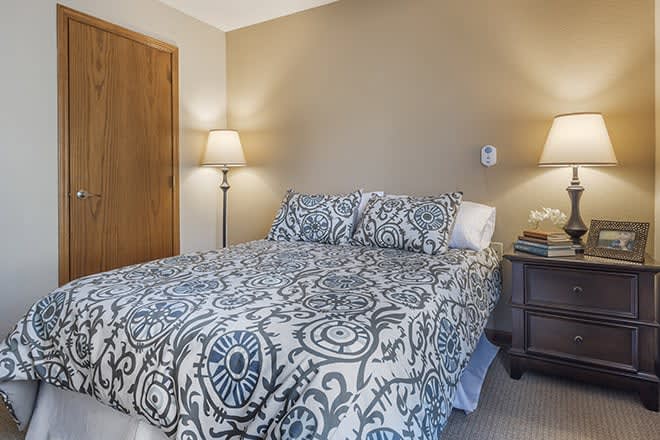 A cozy bedroom with patterned bedding and warm lighting.