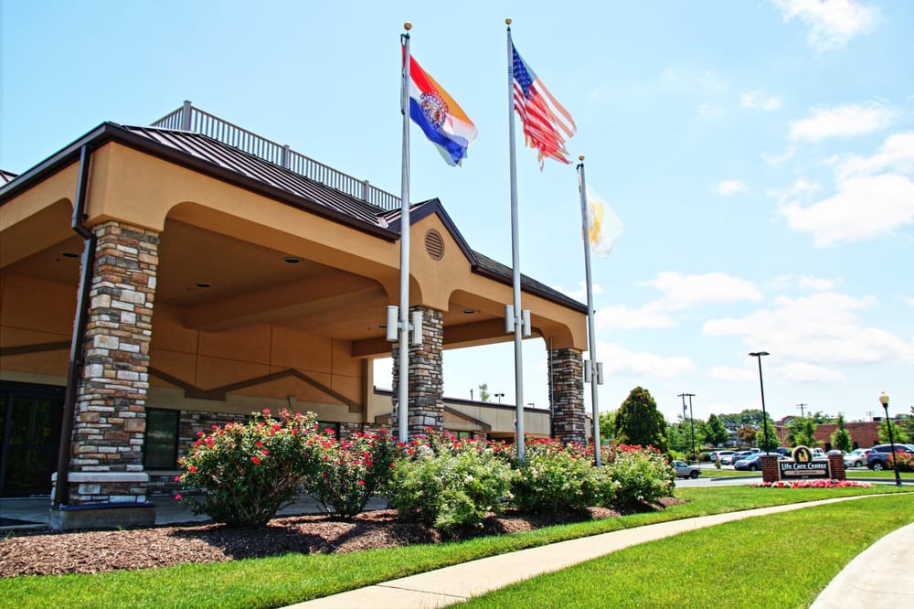 Hotel entrance with flags and well-maintained landscaping.
