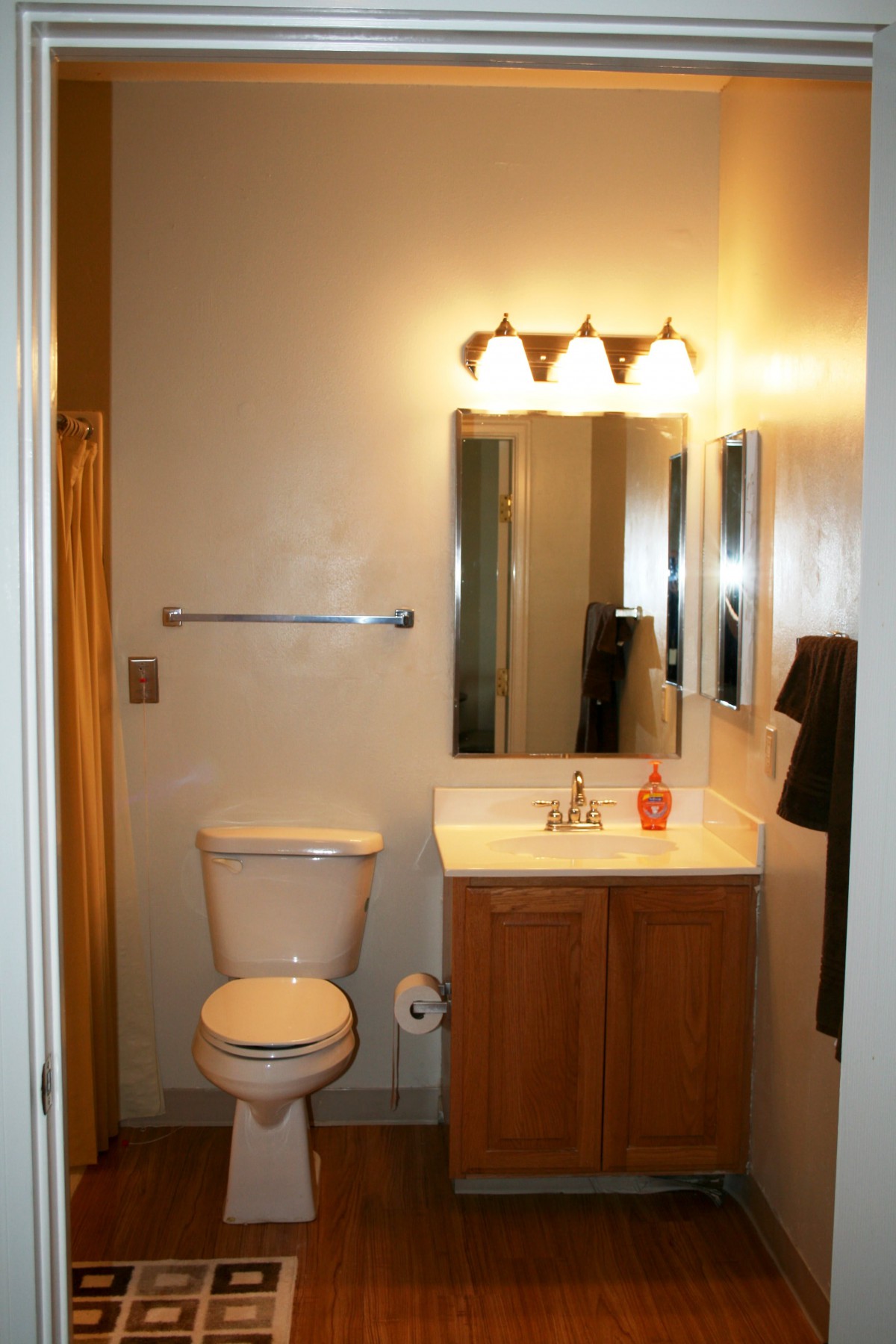 A small bathroom with a toilet, sink, mirror, and overhead light fixture.