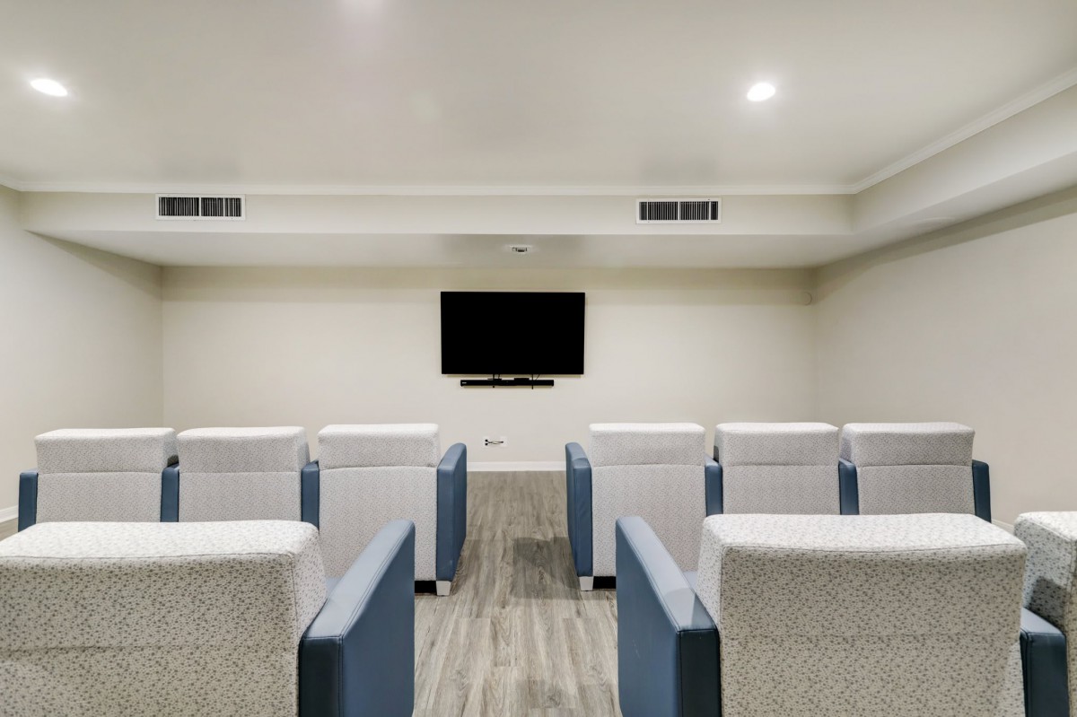 A modern theater room with arranged seating and a large TV screen.