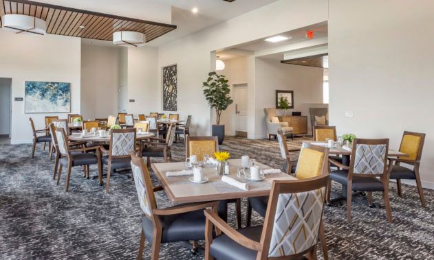 A modern dining room with neatly arranged tables and chairs, featuring neutral tones and elegant decor.