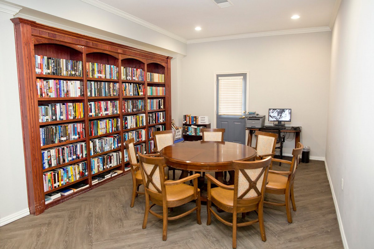 A cozy library reading area with a round table surrounded by chairs and shelves filled with books.