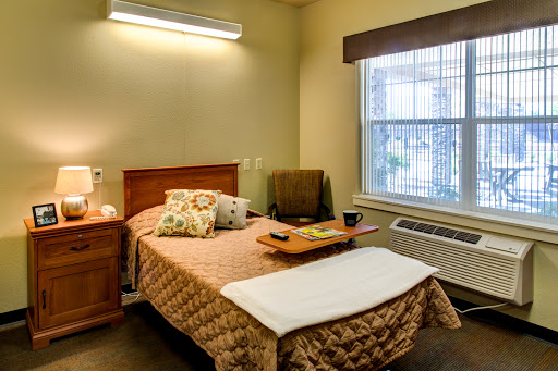 A cozy bedroom featuring a neatly made bed, a nightstand, and natural light coming through the window.