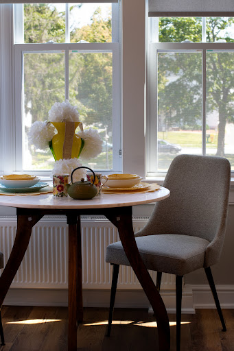 A cozy dining area with a well-set table, featuring vibrant dishes and tasteful decor, illuminated by natural light.