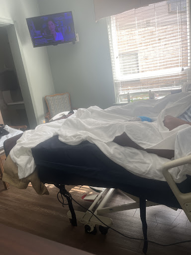 A patient resting in a hospital room, surrounded by medical equipment and comfort items.