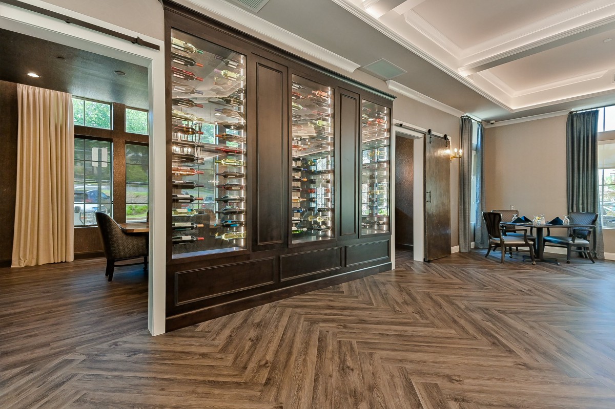 A modern interior featuring a stylish wine cellar with wood flooring and glass display cabinets.