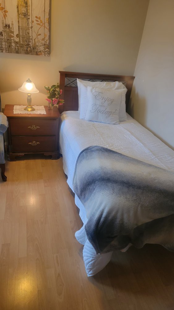 A cozy bedroom with a single bed and nightstand topped with a lamp.