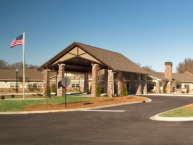 A modern building entrance with stone pillars and a landscaped driveway.