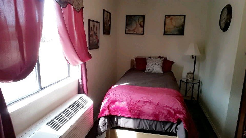 A cozy small bedroom with a single bed and pink decorations.
