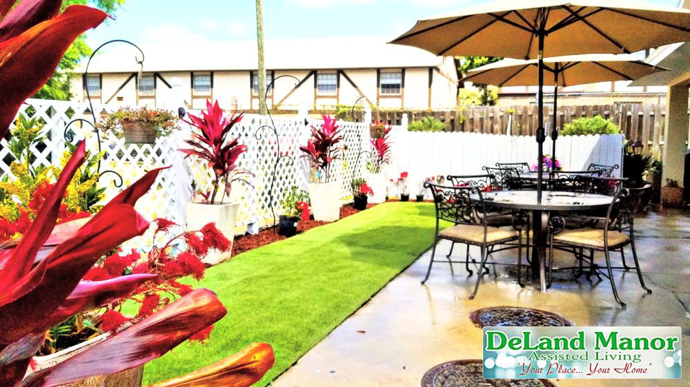 A well-designed patio with outdoor seating, adorned with potted plants and a neatly arranged artificial grass area.