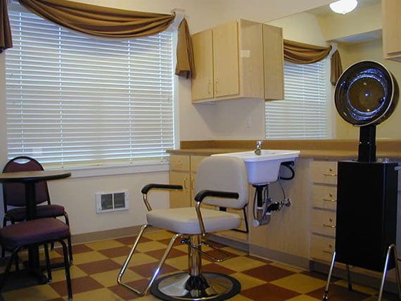 An interior view of a hair salon with chairs, a mirror, and a hairdryer.