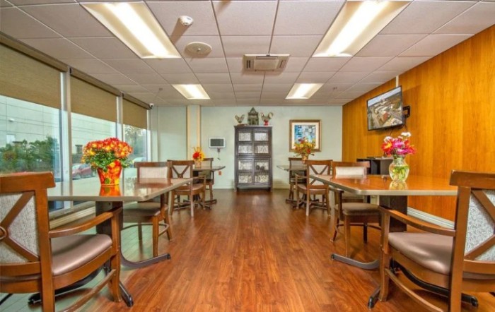 A well-lit dining area with wooden floors and neatly arranged tables and chairs.