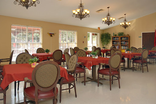 A cozy dining room setup with red tablecloths, elegant chairs, and chandeliers.