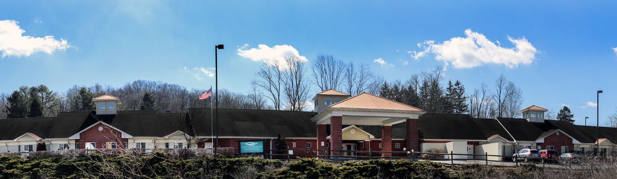 A church building with a prominent cross, surrounded by trees under a clear blue sky.