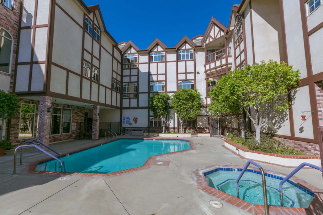 An apartment courtyard featuring a swimming pool and hot tub surrounded by Tudor-style architecture.