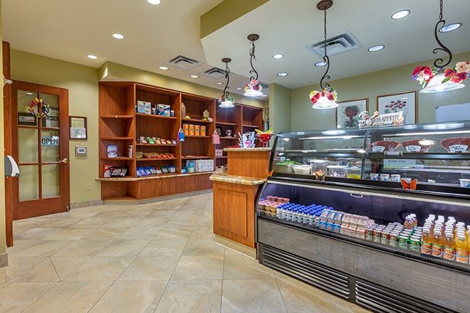 A cozy cafe with a display case full of pastries and shelves stocked with various items.