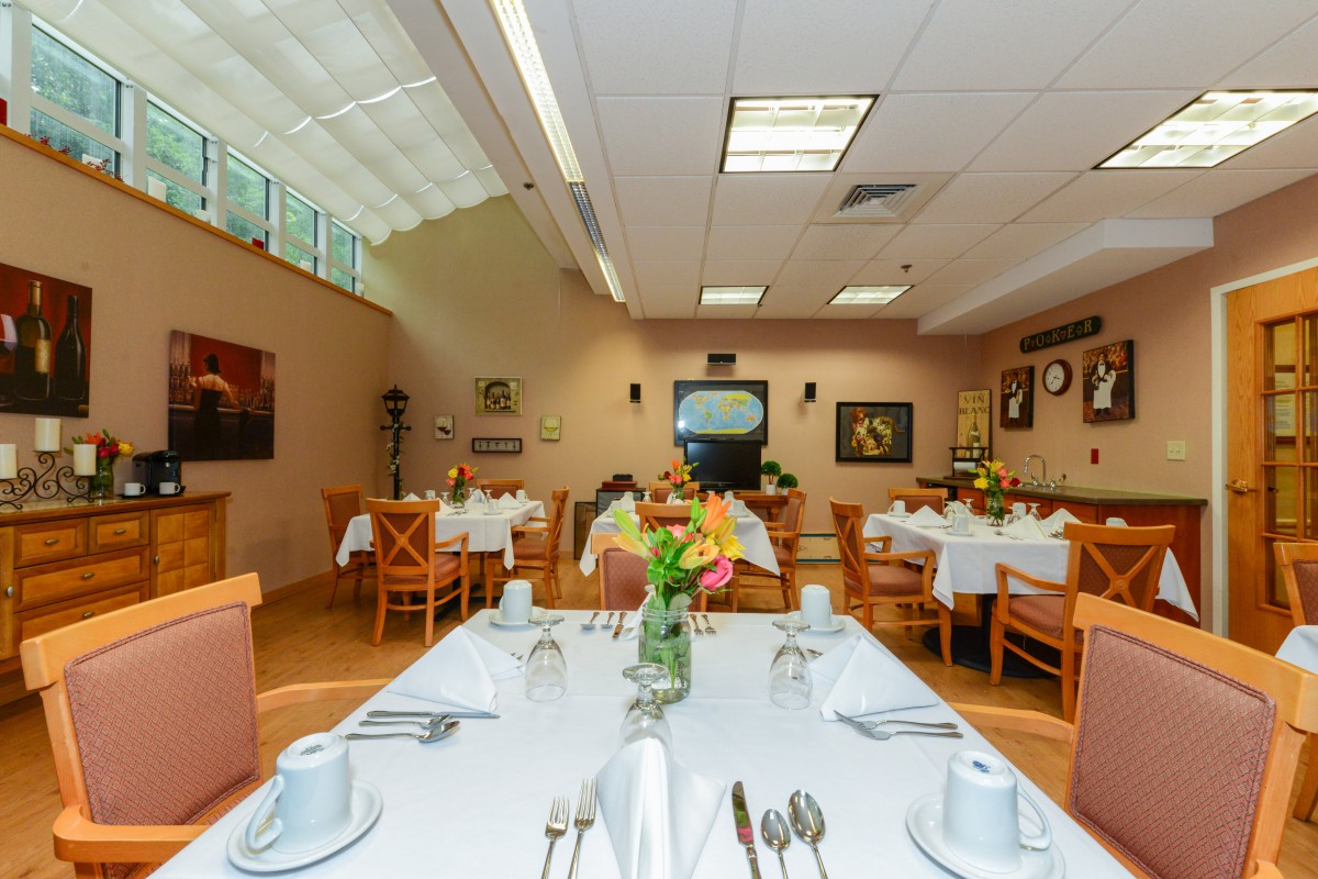 A well-lit dining area with neatly arranged tables and floral decorations.