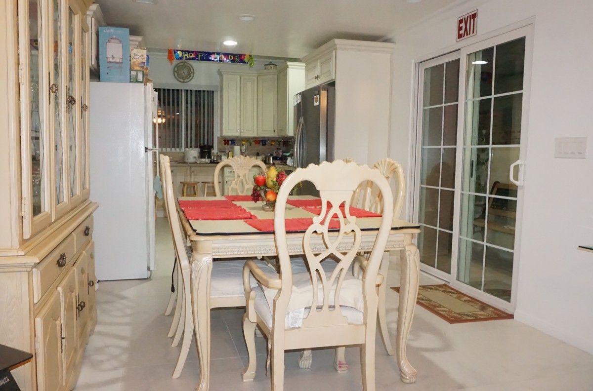 A cozy dining area adjacent to a kitchen, featuring a dining table with chairs and bright decor.