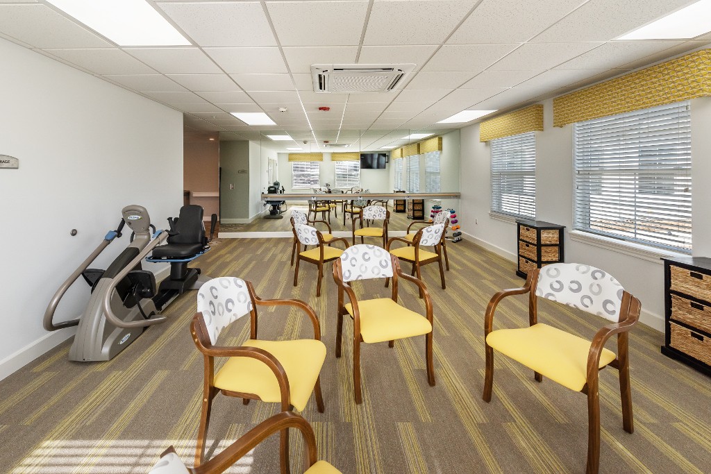 A well-lit exercise room equipped with chairs and fitness machines.