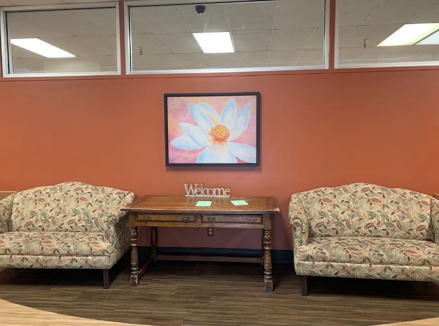 A cozy waiting area with floral upholstery chairs and a vibrant flower painting on the wall.
