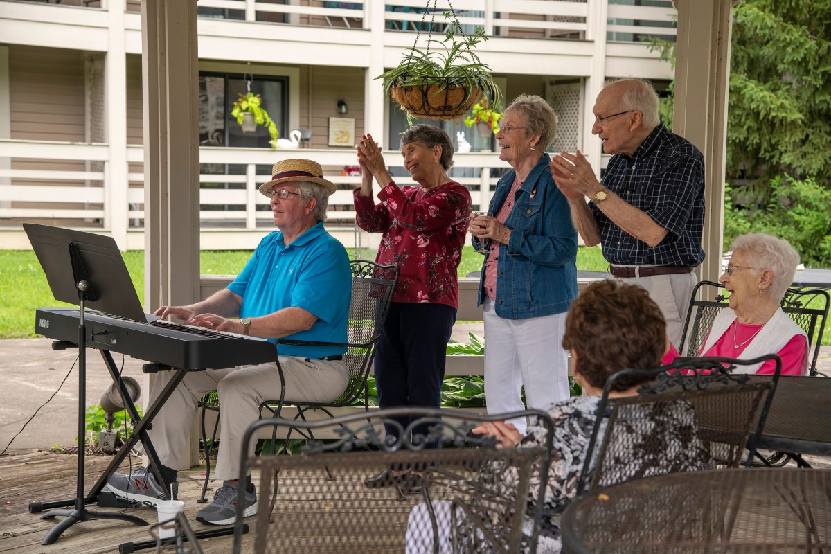 A keyboard player performs outdoors while an appreciative audience claps along.