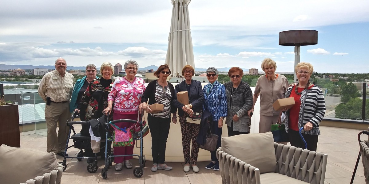 A group of women standing together on a patio with a scenic backdrop.