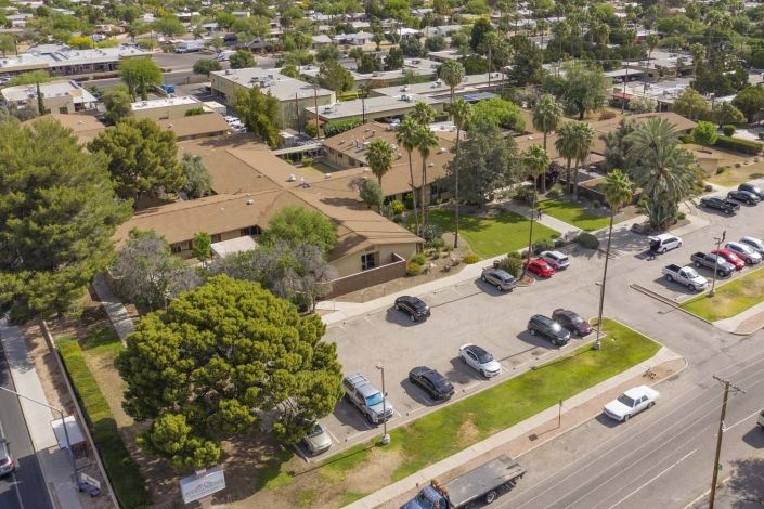 Aerial view of a residential area with houses, parking lot, and surrounding trees.