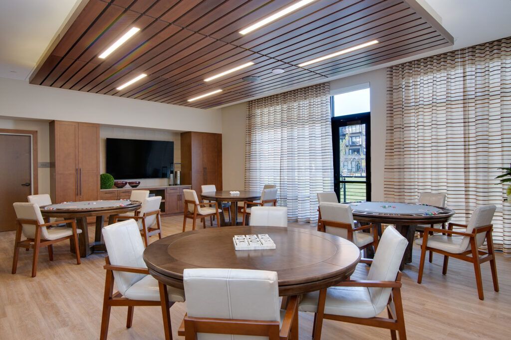 A modern meeting room with round tables, chairs, and a wooden ceiling design.