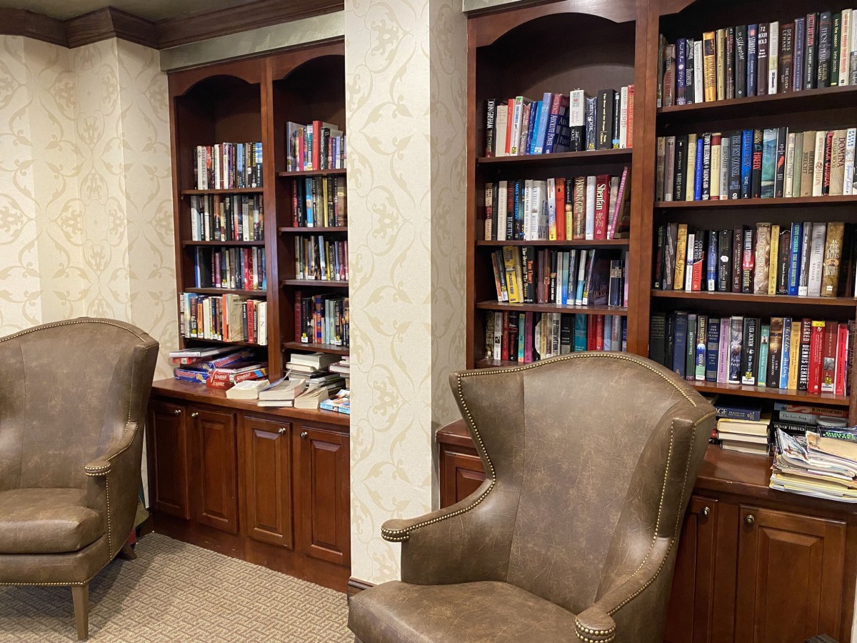 A cozy library corner with leather chairs and wooden bookshelves filled with books.