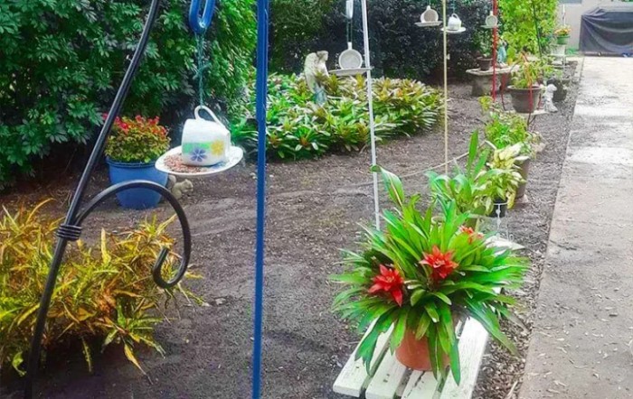 A vibrant garden with a swing adorned with plants and flowers.