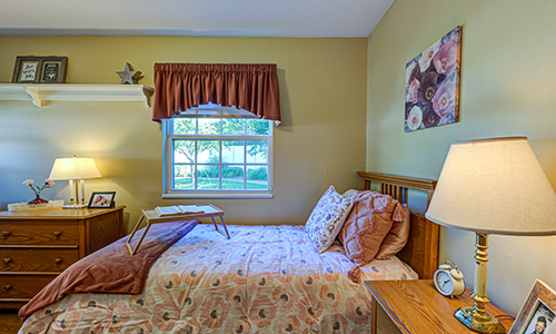 A cozy bedroom with a bed, nightstand, and window.
