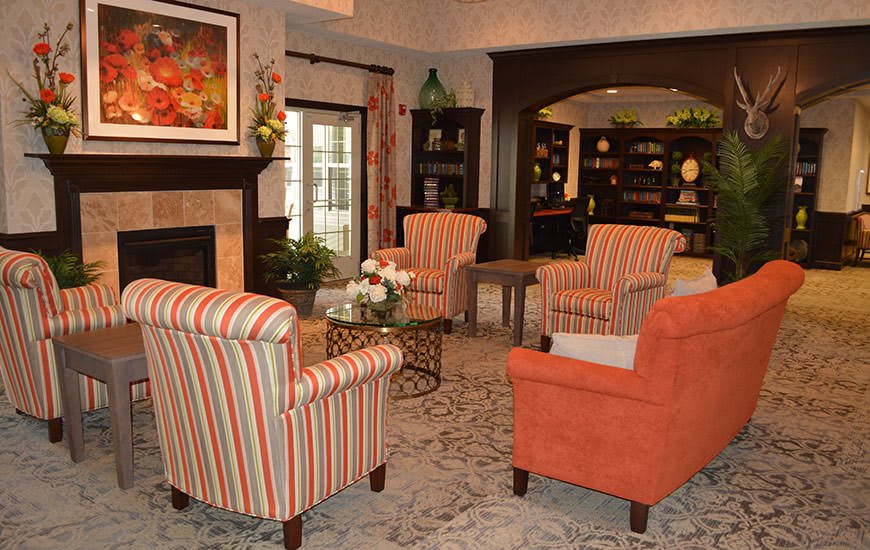 A cozy living room with striped and orange armchairs, a fireplace, and bookshelves.