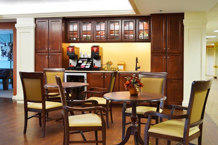 A cozy cafe interior with wooden tables and chairs, featuring a coffee station with machines.