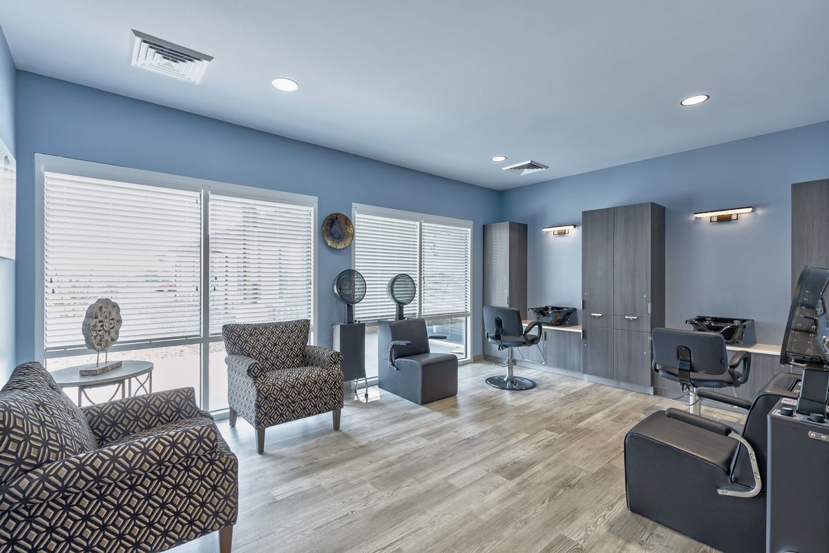A modern salon interior with comfortable seating and large mirrors.