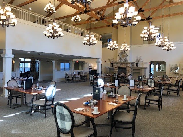 A spacious dining area with elegant chandeliers and neatly arranged tables and chairs.