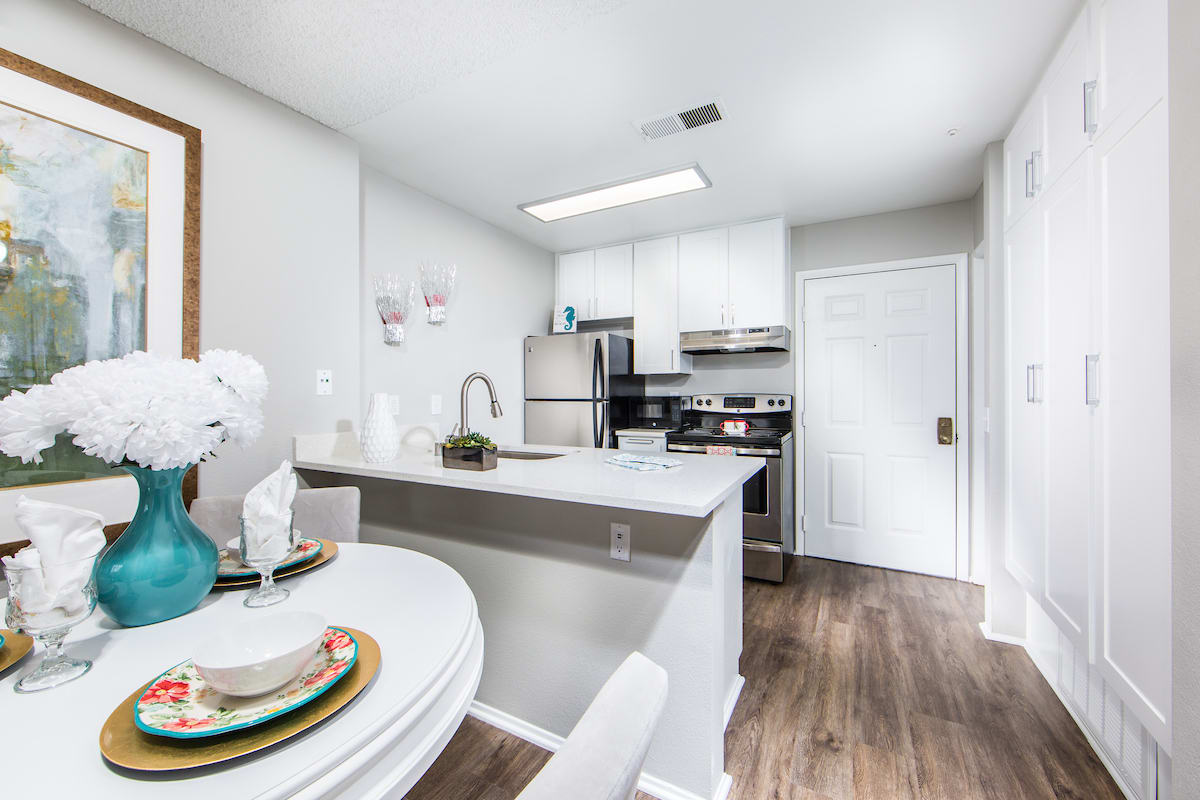A modern kitchen with stainless steel appliances and white cabinetry, complemented by an adjacent dining area.