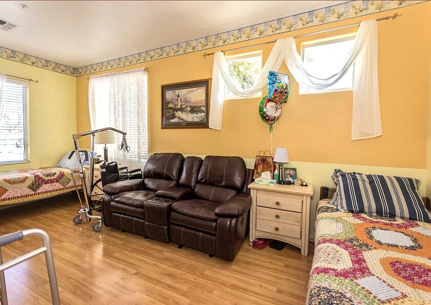 A cozy living room with a leather sofa, bed, and decorative elements like paintings and a wall clock.