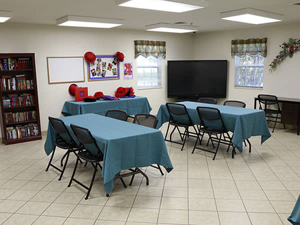 A classroom or meeting room setup with tables, chairs, and a television.