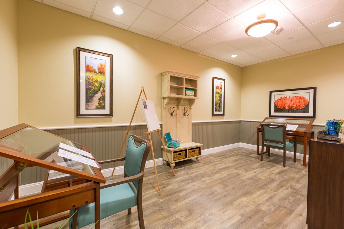 A cozy and well-decorated interior room with desks, chairs, and framed artwork on the walls.