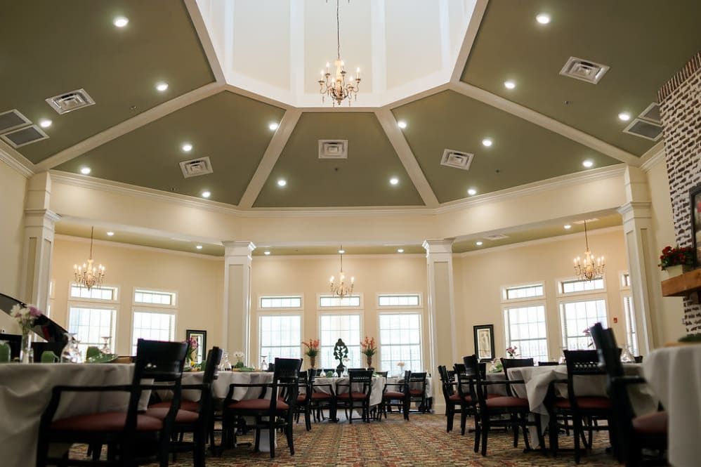 A spacious dining room with elegant interior design featuring a chandelier and neatly arranged tables and chairs.