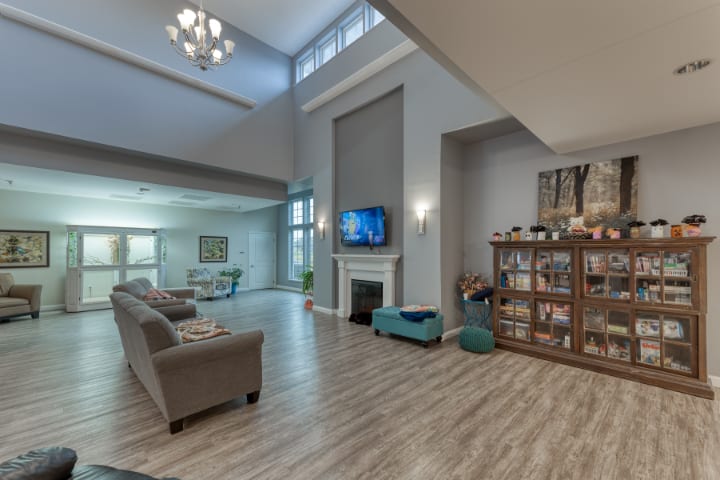 Spacious modern living room with high ceilings, featuring a fireplace and a television, complemented by elegant furniture and hardwood floors.