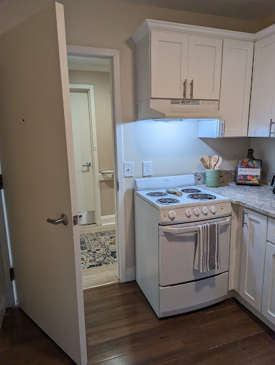 A modern kitchen featuring a stove and an open doorway leading to another room.