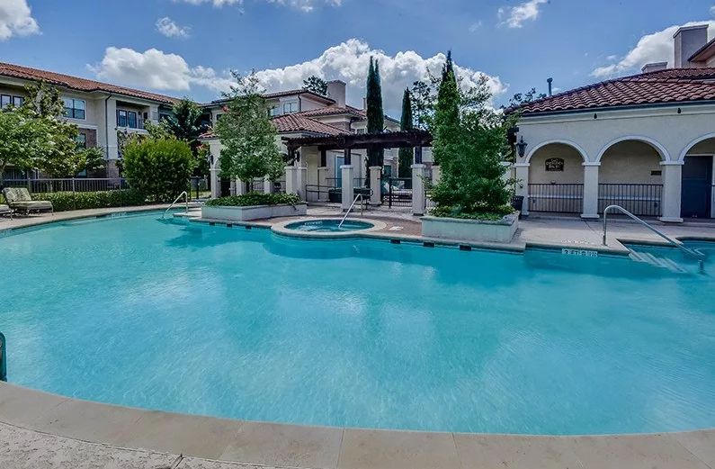 A luxurious outdoor pool adjacent to a beautiful house and garden.