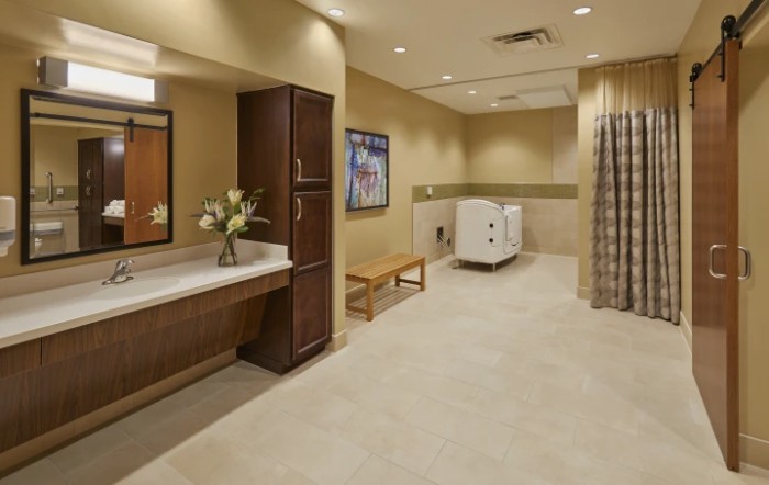 Modern bathroom interior with neutral tones, featuring a sink, mirror, and a bench.