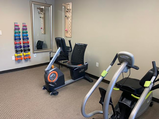 A small fitness area equipped with a recumbent bike, an elliptical machine, and a set of weights.