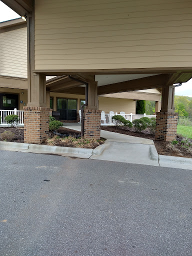 A view of the entrance to a building featuring a covered walkway and landscaped areas.