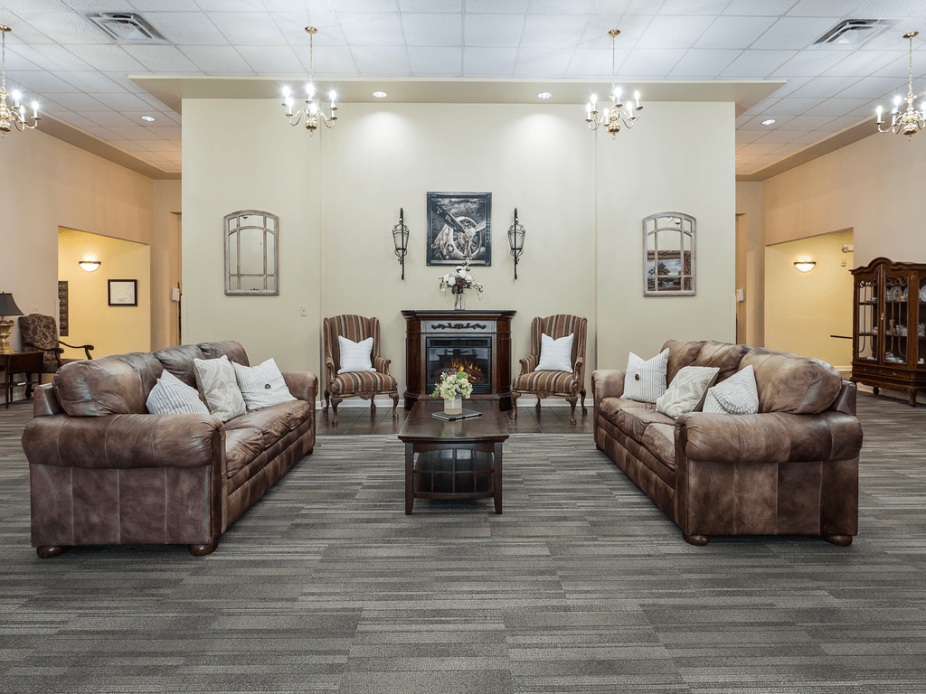 A spacious and well-decorated living room featuring comfortable sofas and armchairs arranged around a central fireplace.