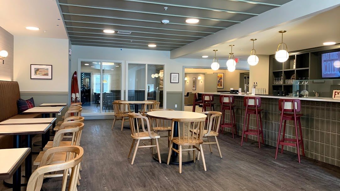 A modern cafe interior with tables, chairs, and a bar counter.
