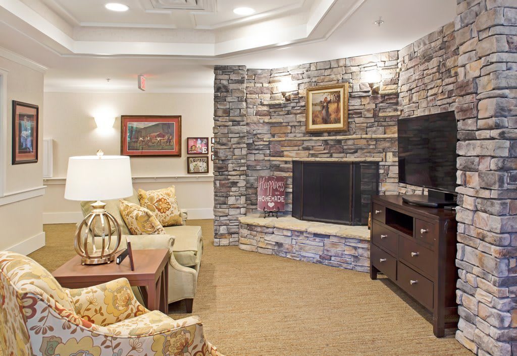 A cozy living room featuring a stone fireplace, television, and tasteful decor.